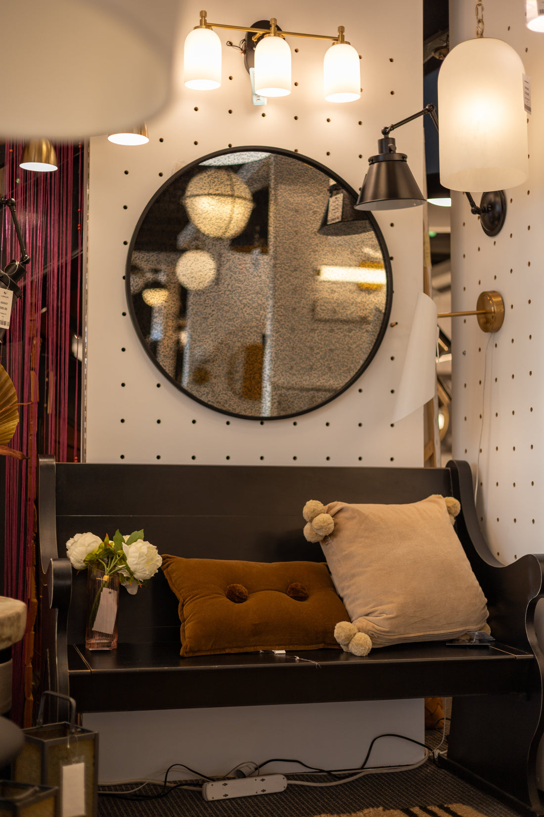Vignette d'entrée avec miroir rond et banc, showroom Luminaire Expert